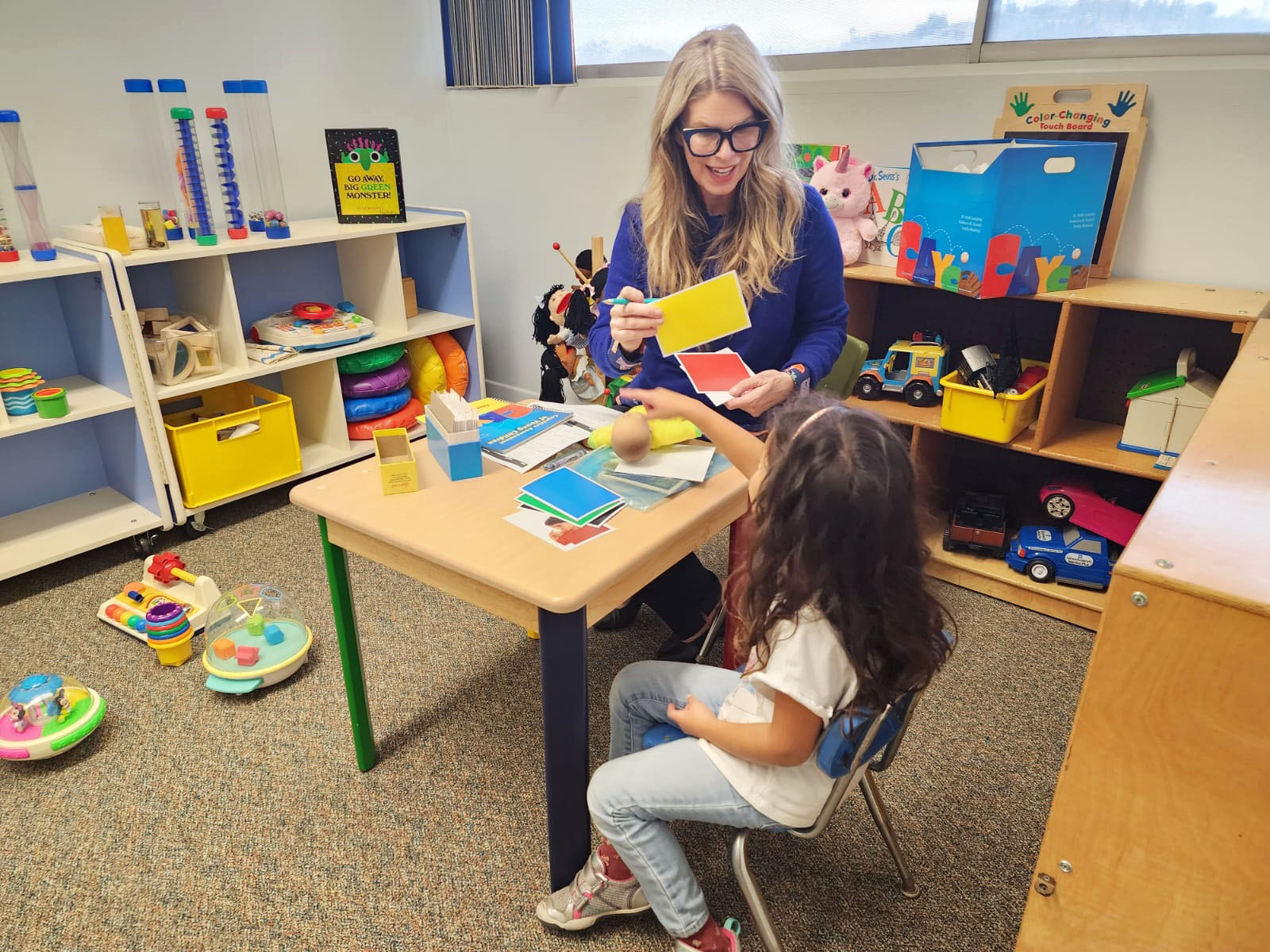 Amy sitting at a table, engaging in an activity with a student