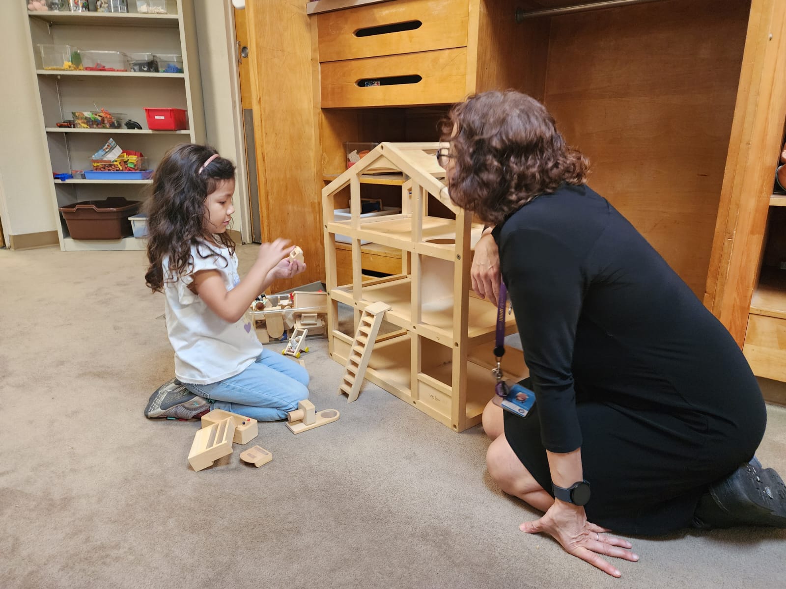 a student plays with a doll-house while the psychologist observes
